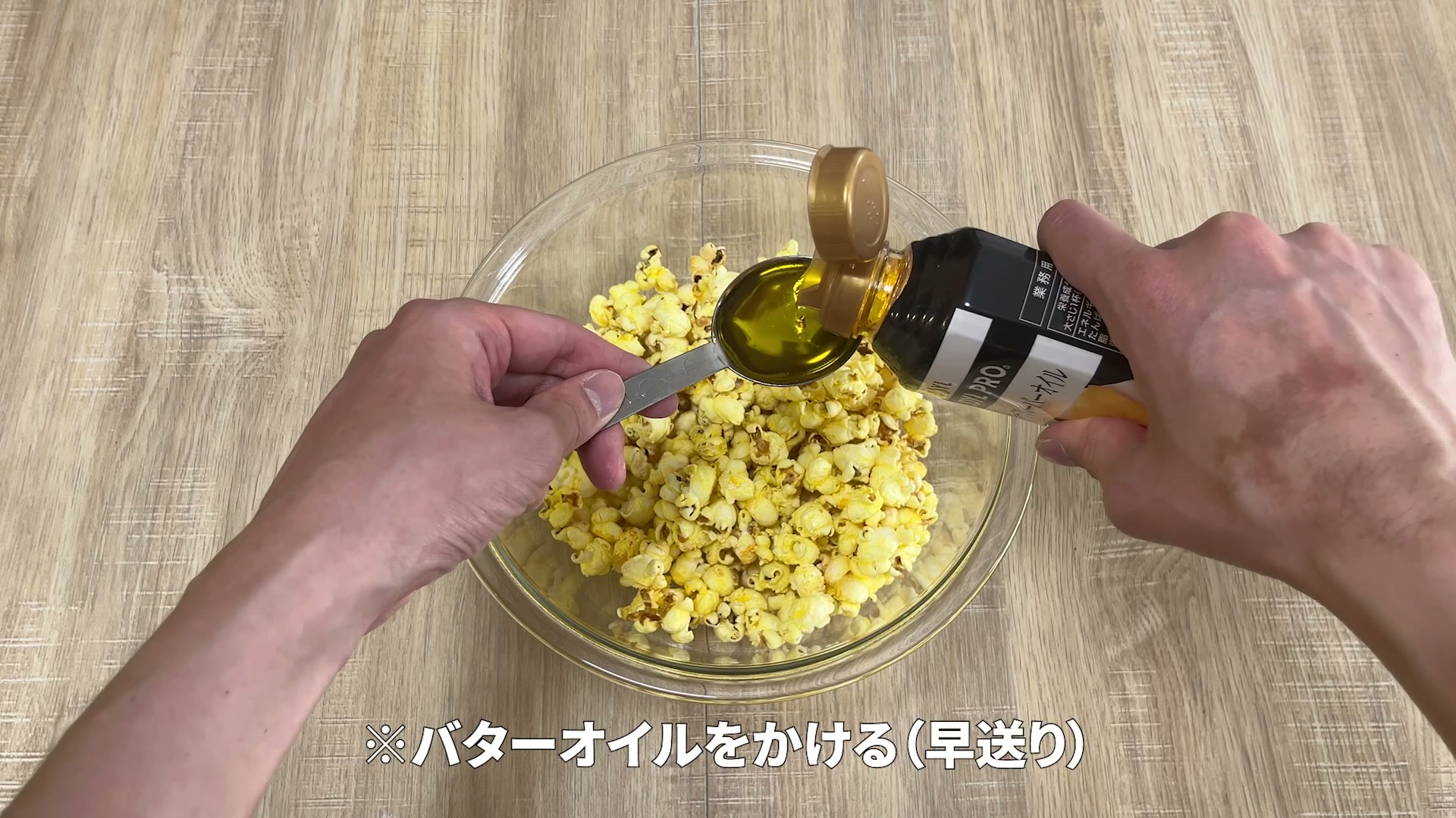 バターオイル大さじ1を計量してポップコーンにかけている様子